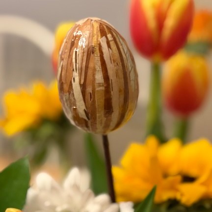 Close up of birch-bark-covered egg decor and flowers, tulip, daisy, spring Easter centerpiece